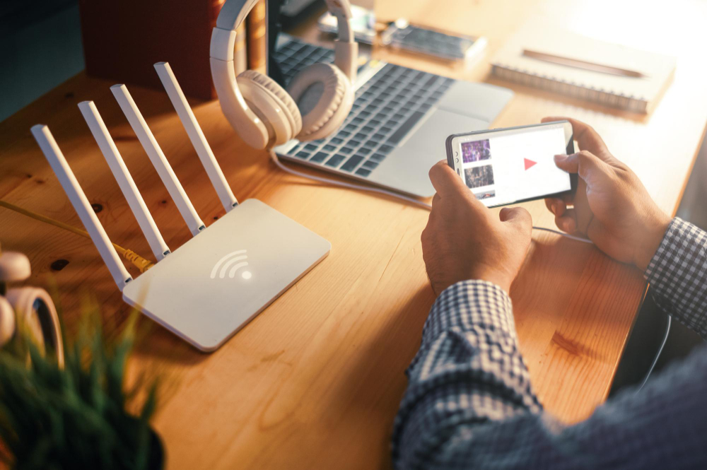 Router, laptop, phone and headphones set up on a desk